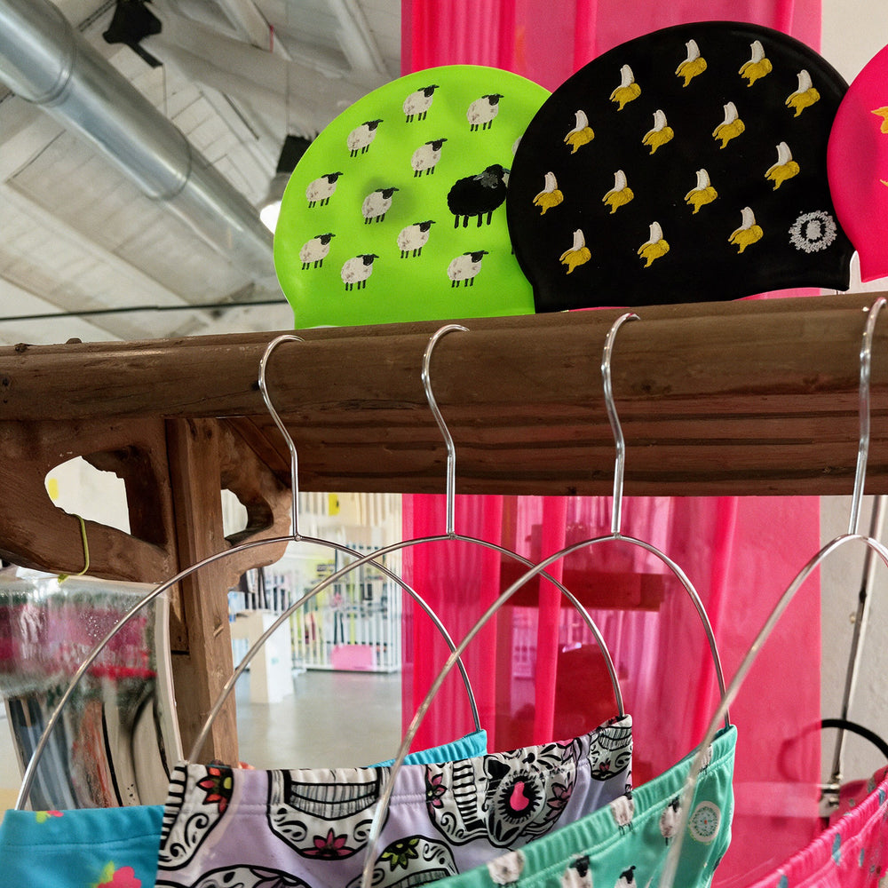 Gorros de natación flúor y bañadores estampados en las estanterías de la tienda